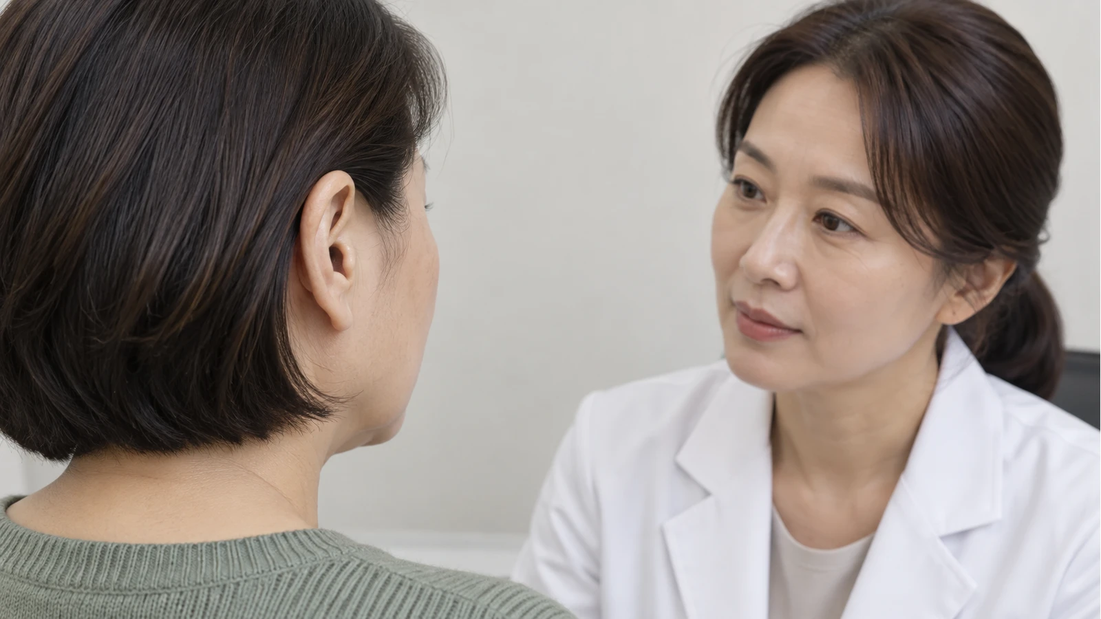 머리를 짧게 정돈한 성인의 귀를 의료진 역할 인물이 접촉 없이 살피는 모습